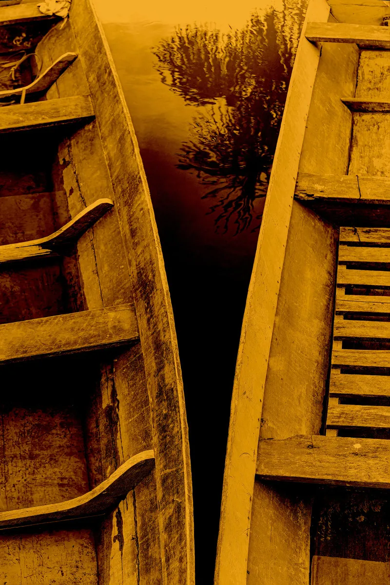 Duas canoas de madeira lado a lado, em detalhe e tons quentes.