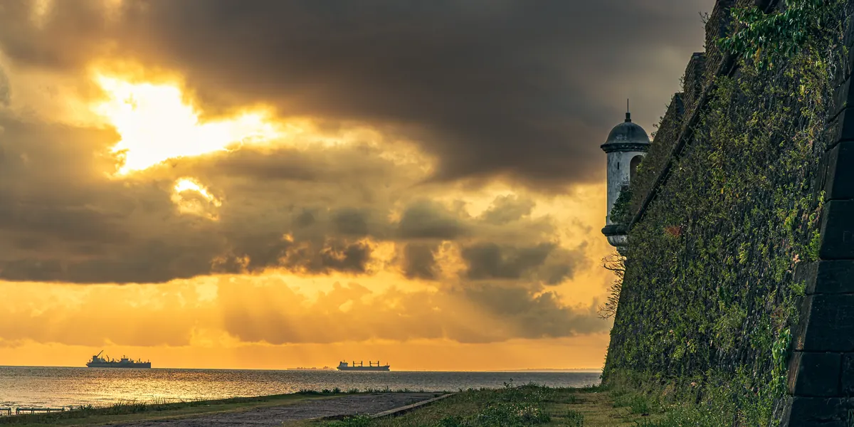 Obra nº 01, Fortaleza de São José e o Sol: o sol rompe as nuvens sobre o rio ao lado da muralha e da guarita da Fortaleza.