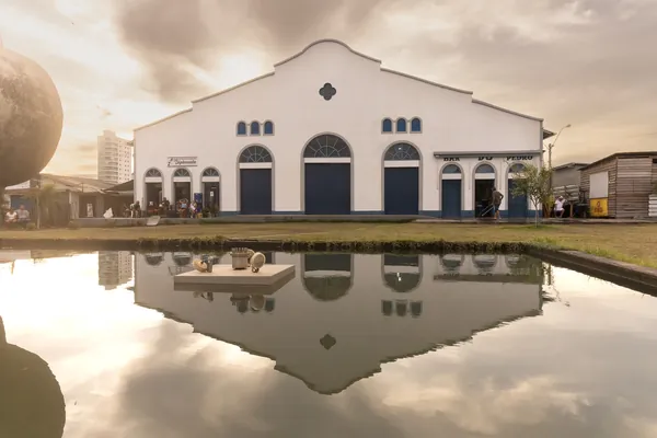 A fachada branca do Mercado Central refletida em um espelho d'água.